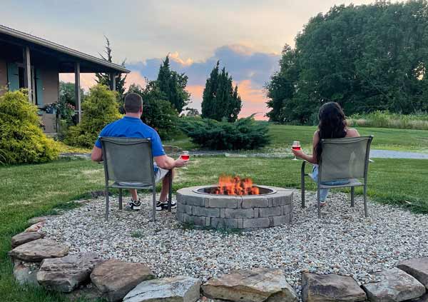 Couple drinking wine next to campfire, watching sunset