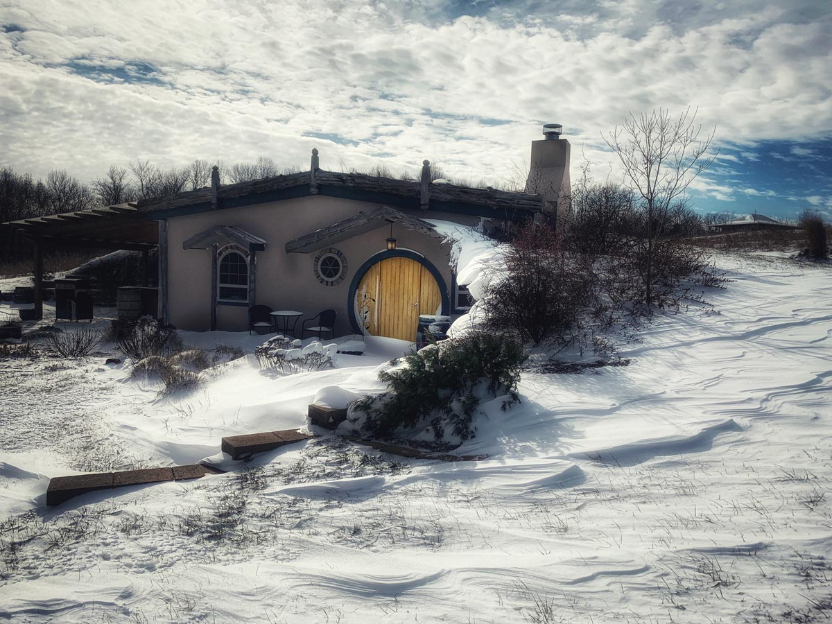 Cabin in the snow with round yellow door and living roof for a cozy Christmas getaway