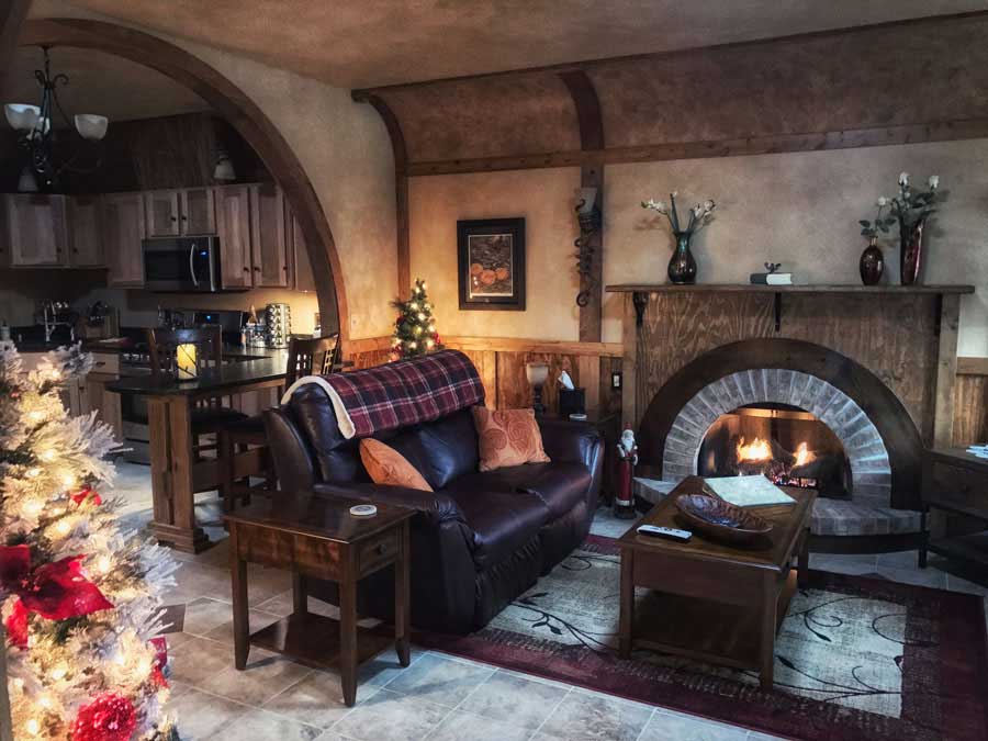 Cozy The Hollow living and kitchen area with curved fireplace and Christmas tree
