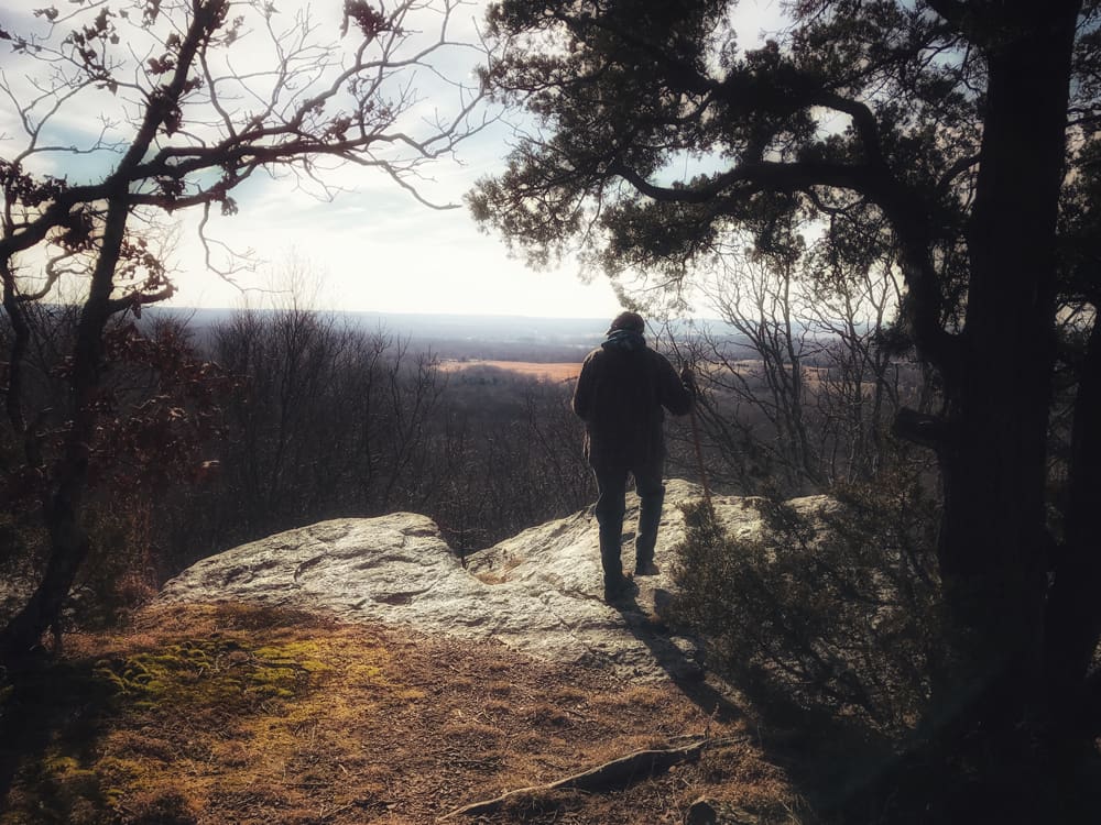 Woman standing on top of a cliff overlooking a long view at Stone Face in the Shawnee National Forest.
