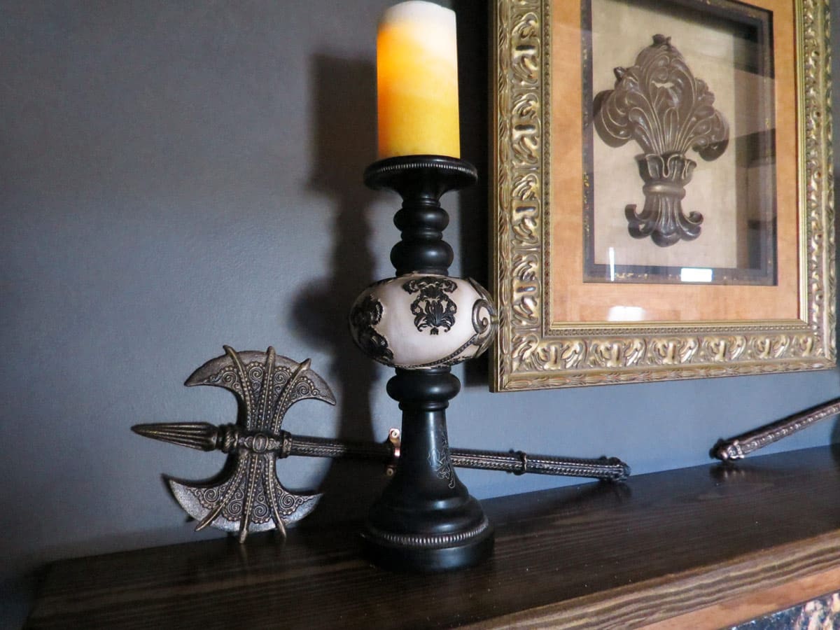 Decorative medieval-style French polearm displayed beside fleur-de-lis artwork in the French Cabin.