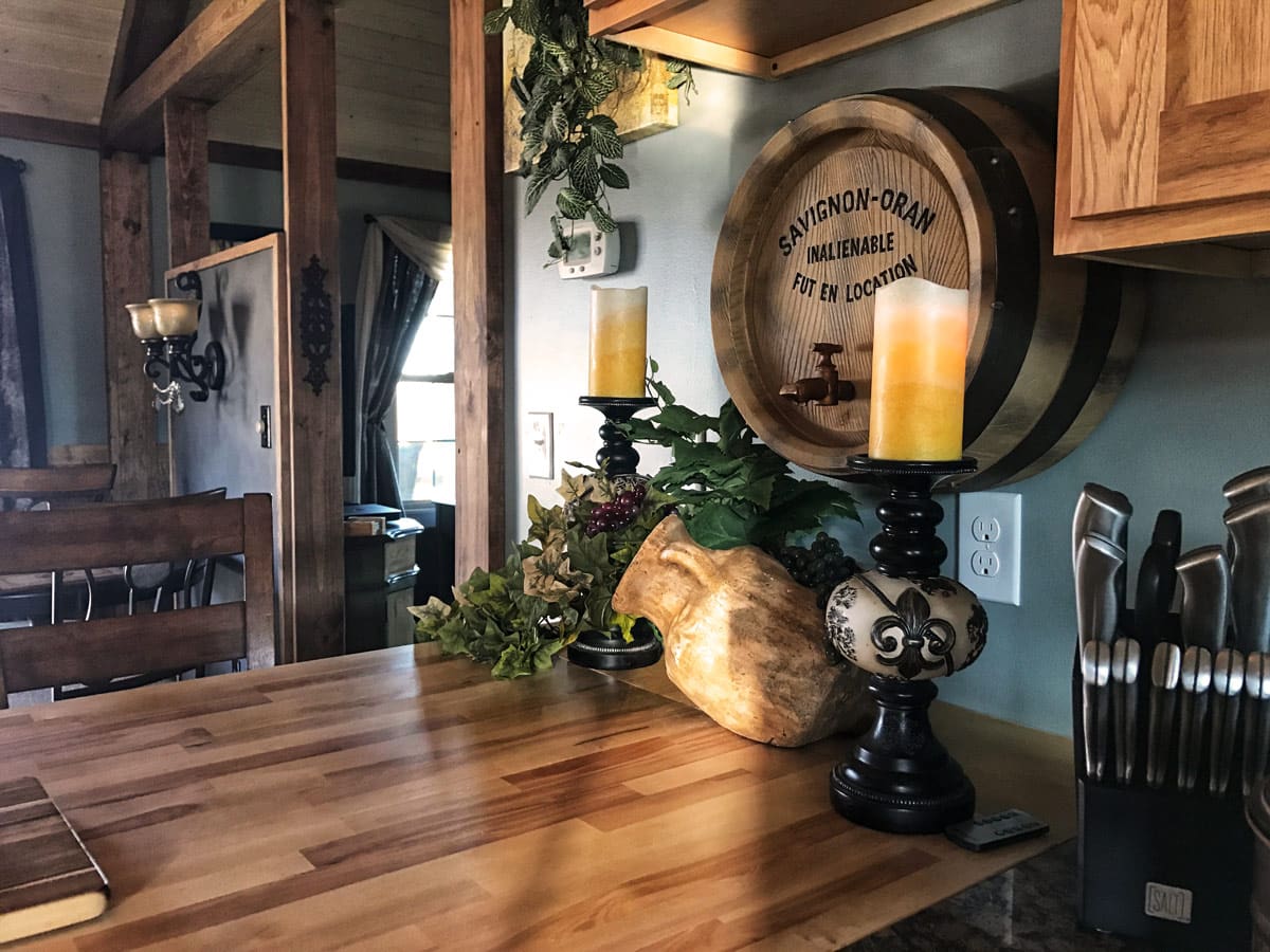 French-inspired kitchen detail featuring a wine barrel accent, decorative candles, and handcrafted butcher block countertop.