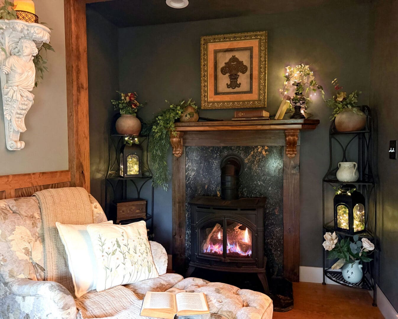 Cozy fireplace alcove in the French Cabin featuring a cast iron stove, custom schist stone surround, lantern lighting, and comfortable reading chair.